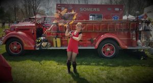Lady Blaze spins fire parasol in front of the Somers CT fire truck.